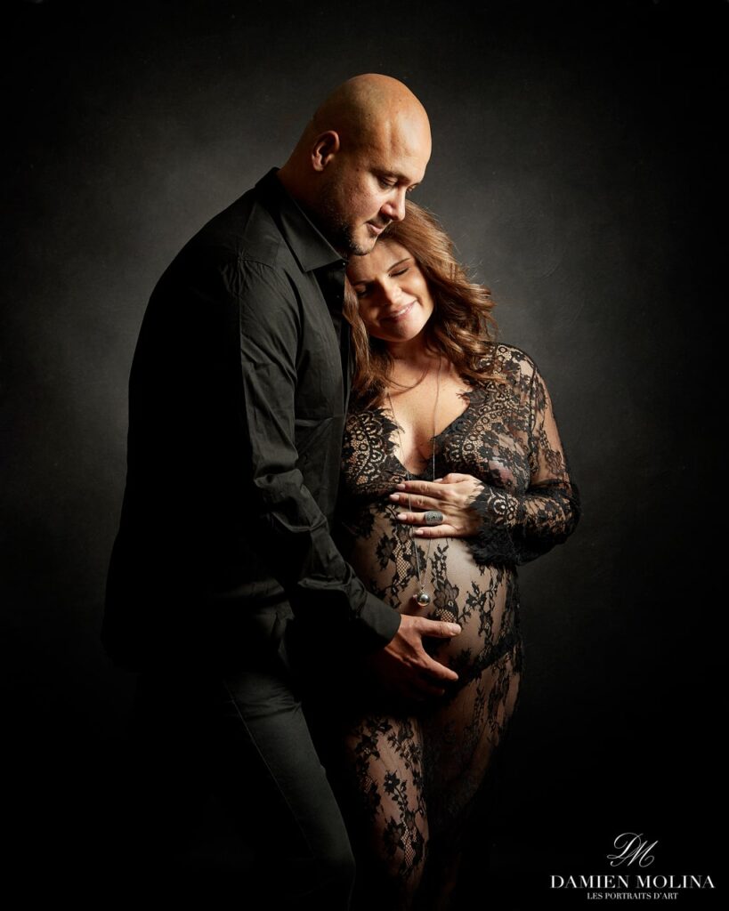 Photographe grossesse en Alsace : Tendresse et élégance à Strasbourg - Damien Molina - Photographe Photo artistique d’un couple attendant un enfant, la future maman en dentelle noire de face, avec le futur papa posant délicatement sa main sous son ventre, capturée à Strasbourg.