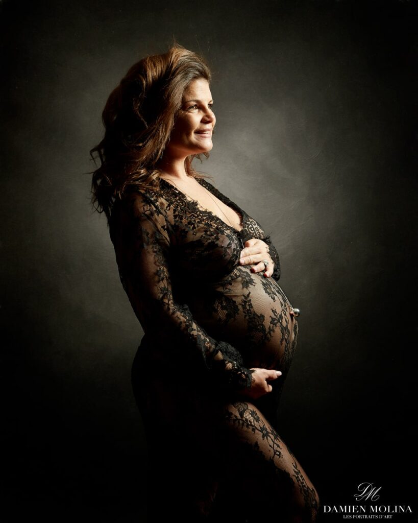 Portrait de grossesse : Élégance en dentelle noire à Strasbourg - Damien Molina - Photographe Photo artistique d’une femme enceinte vêtue d’une robe en dentelle noire, mettant en valeur son ventre arrondi avec une lumière douce, capturée par Damien Molina en Alsace.