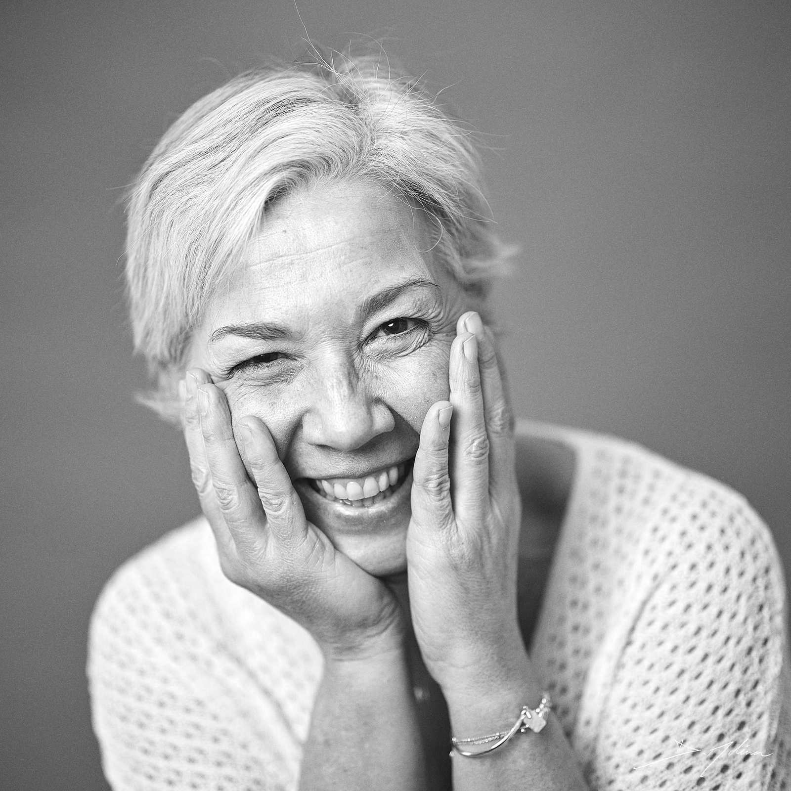 Comme je suis : Portrait authentique et sans retouche à Strasbourg - Damien Molina - Photographe Photo en noir et blanc d'une femme aux cheveux gris, posant les mains devant son visage, réalisée sans retouche dans le cadre de la prestation "Comme je suis" par Damien Molina photographe comme je suis Strasbourg, Alsace.